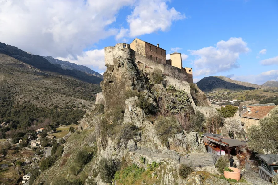 La citadelle de Corte sur son éperon rocheux, vue depuis le belvédère, vallées et montagnes autour.