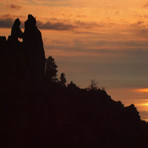 Coucher de soleil sur le golfe de Porto ; en silhouette, le rocher dit « des Amoureux » des calanche de Piana, dont la découpe dessine un cœur.