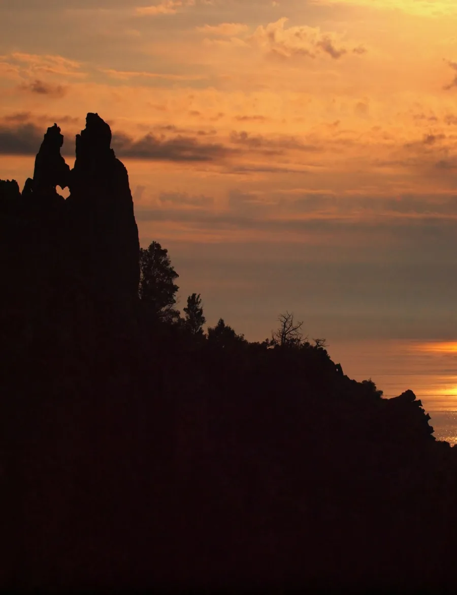 Coucher de soleil sur le golfe de Porto ; en silhouette, le rocher dit « des Amoureux » des calanche de Piana, dont la découpe dessine un cœur.