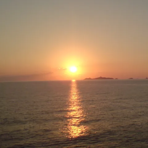 Soleil couchant sur la mer, long reflet doré, et silhouette de l'archipel des Sanguinaires à l'horizon.