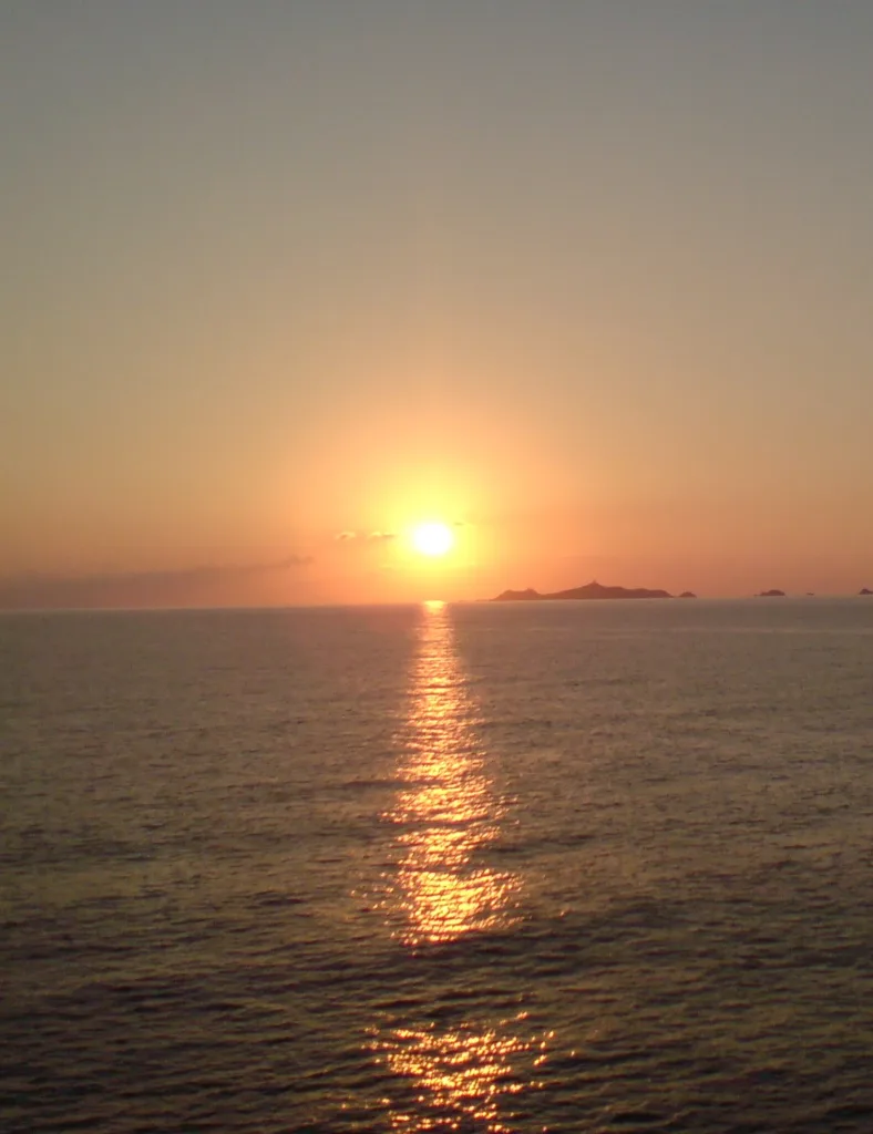 Soleil couchant sur la mer, long reflet doré, et silhouette de l'archipel des Sanguinaires à l'horizon.