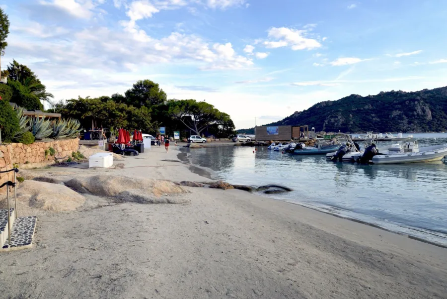 Fin de saison sur la plage de Santa Giulia (septembre 2016) : sable presque vide, semi-rigides amarrés au ponton, colline de granit en fond.