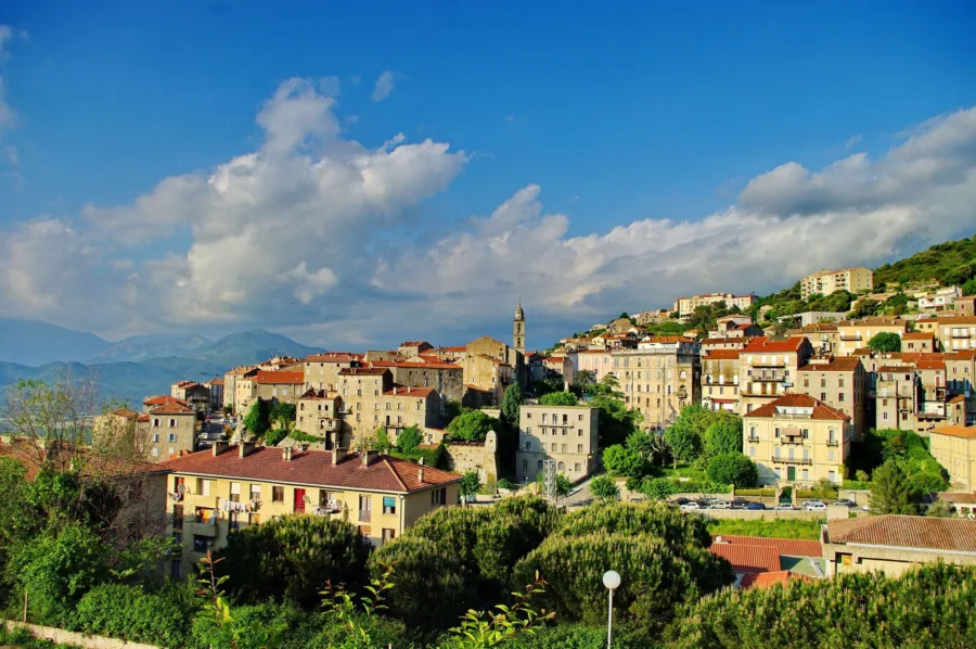 La vieille ville de Sartène, maisons de granit étagées et clocher, sous un ciel de nuages.