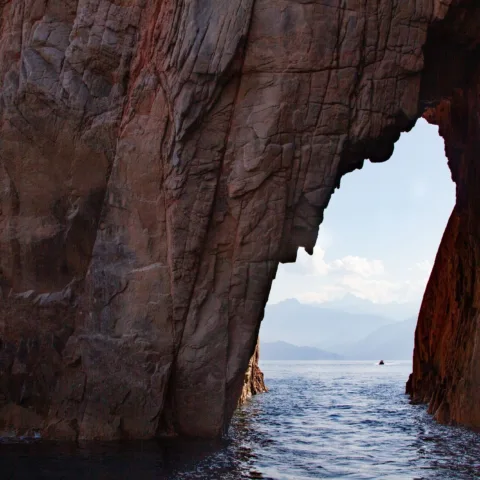 Arche de rhyolite rouge dans la réserve naturelle de Scandola, vue depuis la mer.