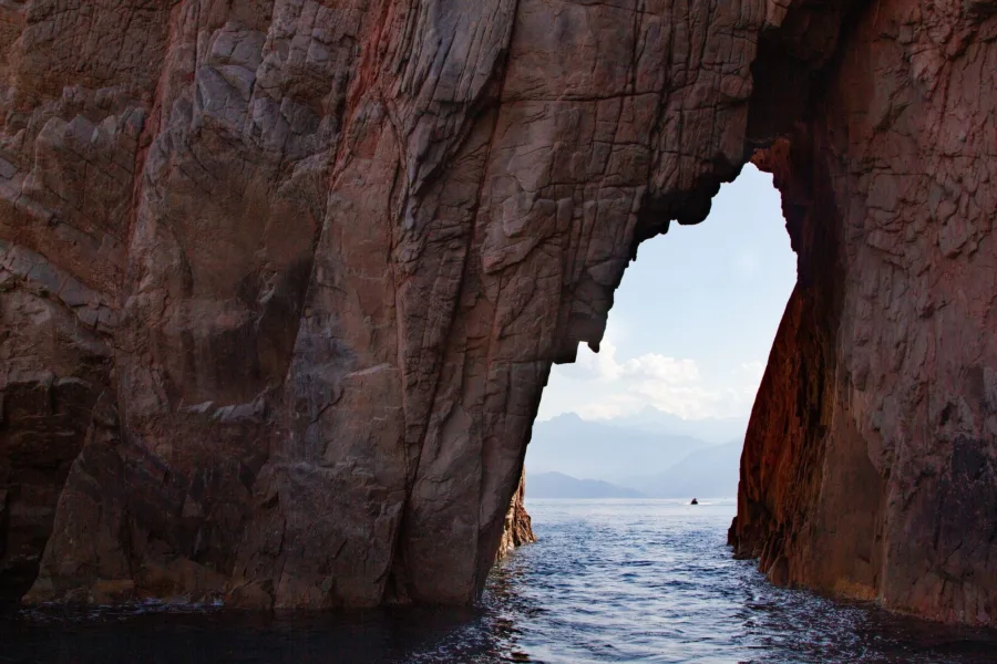 Arche de rhyolite rouge dans la réserve naturelle de Scandola, vue depuis la mer.